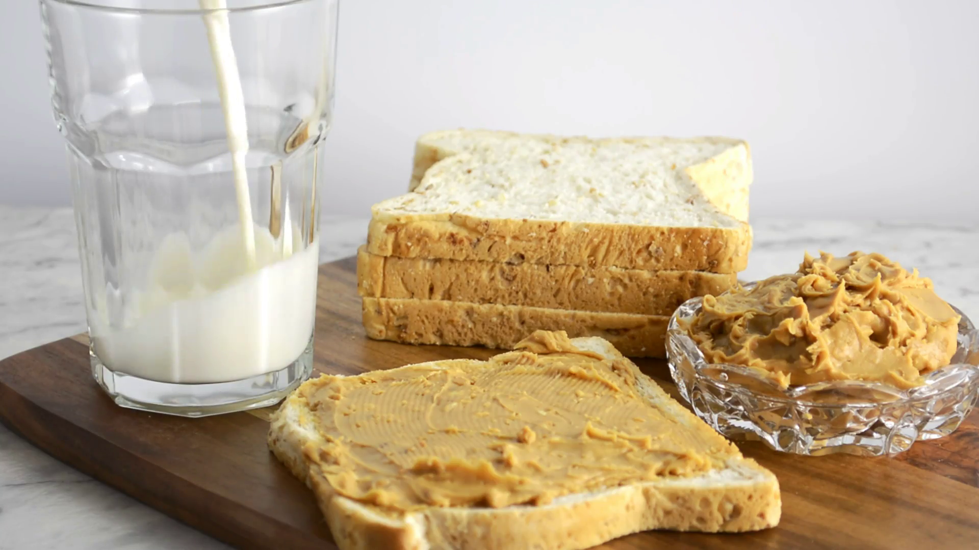 Boterham besmeerd met pindakaas en een glas melk